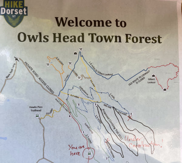 The town’s “Welcome to Owls Head Town Forest” trail map posted at the Raptor Lane trailhead, showing hiking and mountain-bike trails, with “You are here” and “Under construction!” written on it by hand